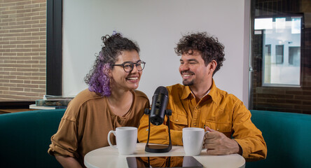 Happy latin american couple chatting on podcast talk show, recording live content with sound...