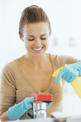 Happy young housewife cleaning in bathroom