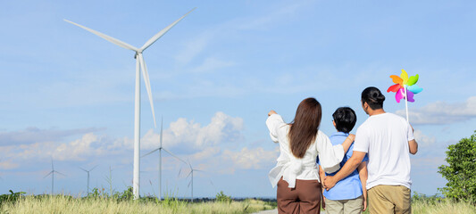 Concept of progressive happy family enjoying their time at the wind turbine farm. Electric generator from wind by wind turbine generator on the country side with hill and mountain on the horizon. © InfiniteFlow