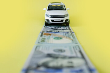 White toy car on money road on yellow background