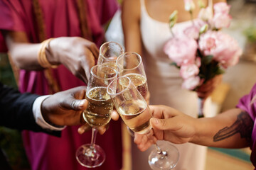 Closeup of group of friends celebrating and toasting with Champagne glasses during wedding reception party