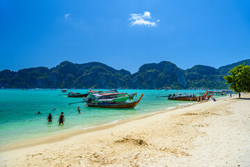 Pretty women girls wimming in azure sea and long tail boats on a white sandy beach on Ko Phi Phi Don Island on a sunny day, Ao Nang, Mueang Krabi District, Krabi, Andaman Sea, Thailand