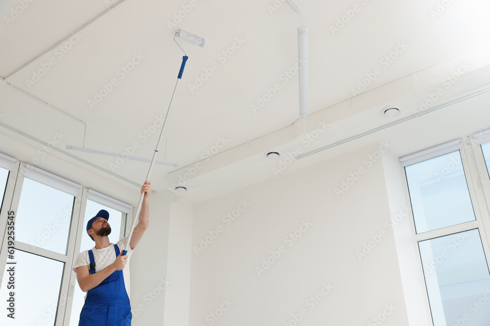 Canvas Prints Worker in uniform painting ceiling with roller indoors. Space for text