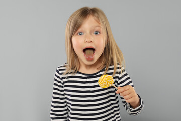 Portrait of cute girl with lollipop on light grey background