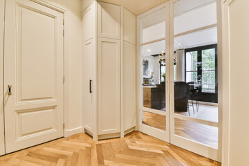 a room with wooden floors and white closets in the middle part of the room there is a large mirror on the wall