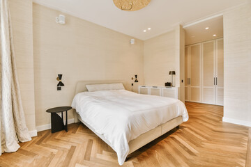 Fototapeta na wymiar a bedroom with wood flooring and white sheets on the bed, there is a large window in the room