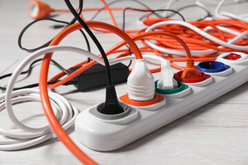 Power strip with different electrical plugs on white laminated floor, closeup