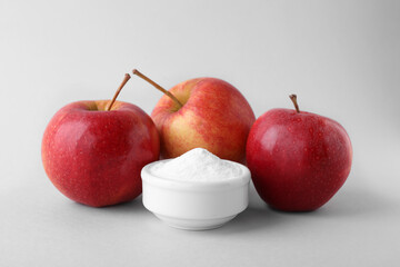 Bowl with sweet fructose powder and ripe apples on white background