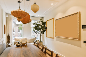 a living room and dining area with wood flooring, white walls, wooden furniture and large framed pictures on the wall