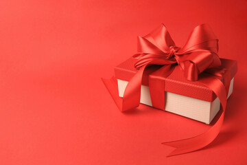 Beautiful gift box with bow on red background. Space for text