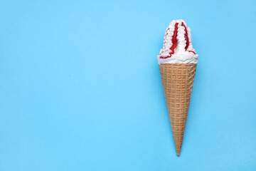 Delicious ice cream with raspberry jam in waffle cone on light blue background, top view. Space for text
