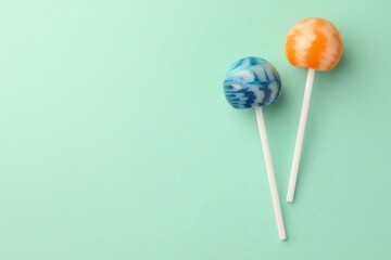 Tasty lollipops on turquoise background, flat lay. Space for text