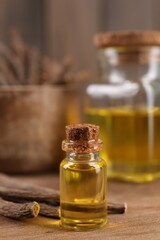 Dried sticks of licorice roots and essential oil on wooden board, closeup