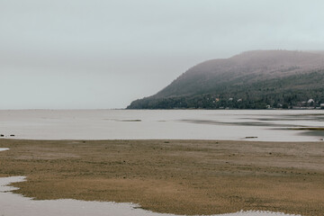 vue d'une côte avec une colline lors d'une journée grise avec un fleuve et une plage en avant...