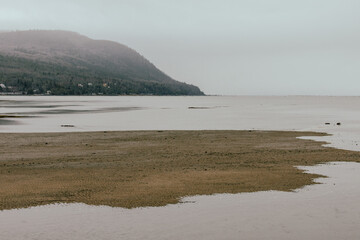 vue d'une côte avec une colline lors d'une journée ennuagée avec un fleuve et une plage en avant plan en été lors d'une marée basse