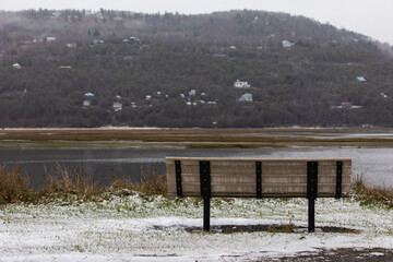 vue du dos d'un banc publique en bois avec vue sur la colline en face lors d'une journée grise