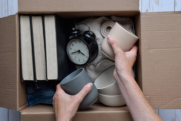 Person's hands placing used personal belongings items into cardboard box
