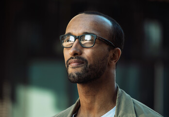 Obraz premium A young unshaven afro american smiling man wearing eyeglasses on the street.