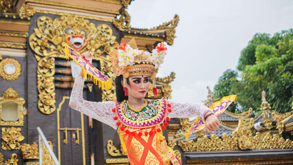 girl wearing Balinese traditional dress with a dancing gesture on Balinese temple background with...