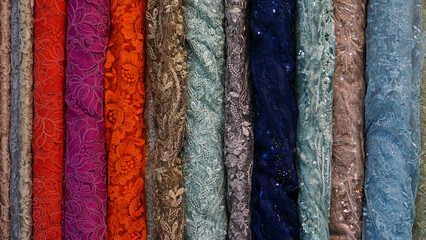 various types of colorful rolled fabrics with knitting neatly arranged for the background
