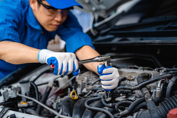 Obraz premium Close up of view Auto mechanic repairman using a socket wrench working engine repair in the garage, changing spare parts, checking the mileage of the car, checking and maintenance service concept.