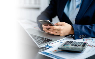 Close up view of Businesswomen or Accountants using smartphones while working analyzing business report graphs and finance charts at the workplace, financial and investment concept.
