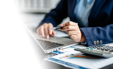 Close up of Businesswomen or Accountant working on laptop computer with analytic business report graph and finance chart at the workplace, financial and investment concept.