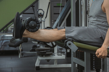 Leg extension exercise on the simulator in the gym. Close-up