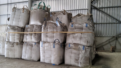 A large number of large bigbag poly sacks of industrail waste are stacked 3 layers .