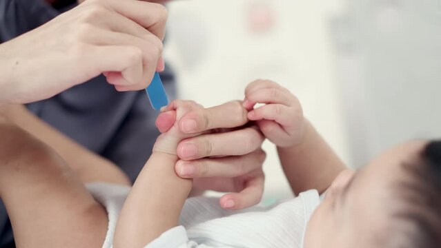 Loving Care, Closeup of Mother's Hand Expertly Cutting and Filing Baby's Nails, Ensuring Hygiene and Health - 4K Footage.