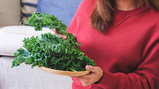 Closeup image of a woman holding and picking up kale leaves