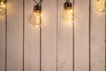 Top lay photo of wood texture, and Edison lights draped along the top of the frame. The lights are arranged in a way that creates a sense of warmth and ambiance. Photo leaves plenty of space for text 