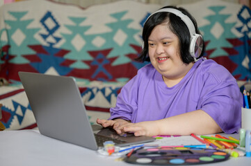 Asian woman with down syndrome wearing casual clothes using laptop at home Asian girl with down...