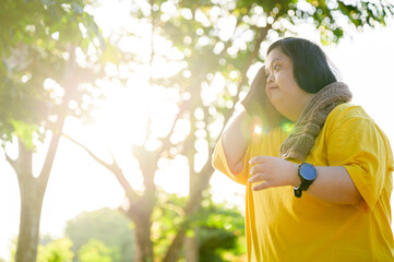 Asian girl with down syndrome exercising By walking to burn fat and jogging to exercise in the park.