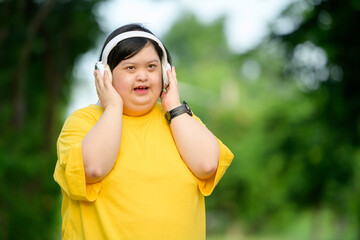 Asian girl with Down syndrome wearing headphones Smiling with happiness in the park in the middle of nature