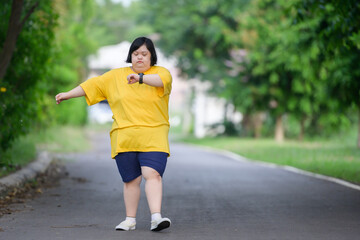 young woman with down syndrome exercising by walking to burn fat and running slowly fat young woman exercising in the park in the middle of nature