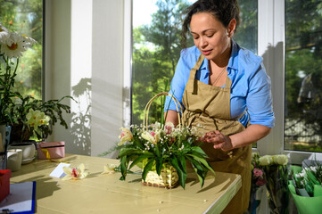 Multi-ethnic woman, inspired florist working on flower arrangement in floral design studio. Floristics. Floral shop