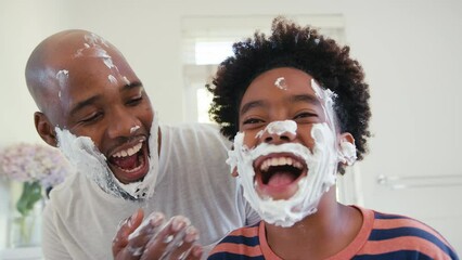 Close up of father and son at home having fun playing with shaving foam in bathroom making a mess together - shot in slow motion - Powered by Adobe