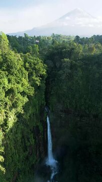 Aerial view of Coban Kapas Biru waterfall with Semeru Volcano in the background. East Java, Indonesia