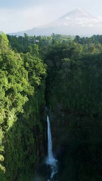 Aerial view of Coban Kapas Biru waterfall with Semeru Volcano in the background. East Java, Indonesia