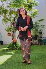 Asian woman wearing traditional Javanese clothing called Kebaya, walking in the garden
