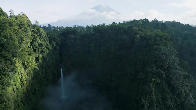 Aerial view of Coban Kapas Biru waterfall with Semeru Volcano in the background. East Java, Indonesia