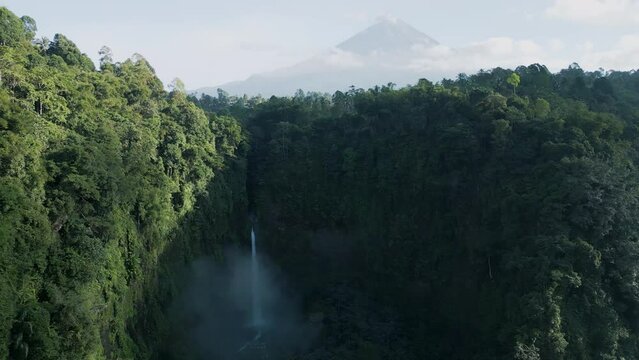 Aerial view of Coban Kapas Biru waterfall with Semeru Volcano in the background. East Java, Indonesia