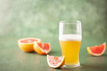 Boozy Refresing Cold Grapefruit Beer in a Pint Glass and Bottle on table. Copy space