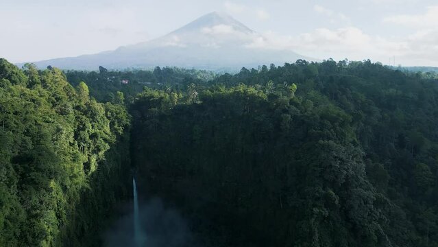 Aerial view of Coban Kapas Biru waterfall with Semeru Volcano in the background. East Java, Indonesia
