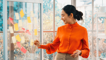 Business people work on project planning board in office and having conversation with coworker...