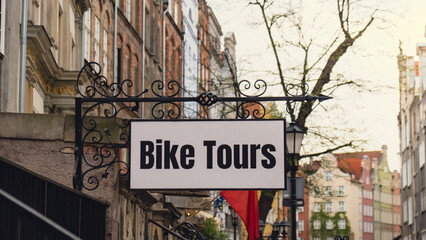 Obraz premium City bike tours in the old town with text sign. Guided tour in Gdansk by bike. Tourist attraction travel destination. Rental bicycle tour