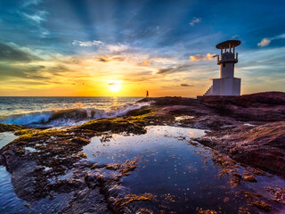 Oceanic Splendor: Lighthouse, Rugged Rocks, and the Glowing Evening Sun