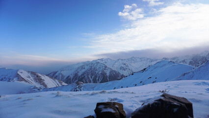 An ocean of clouds in the snowy mountains at dawn. White clouds are like a carpet in a gorge. Waves...