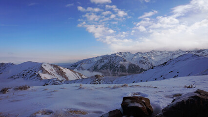 An ocean of clouds in the snowy mountains at dawn. White clouds are like a carpet in a gorge. Waves...
